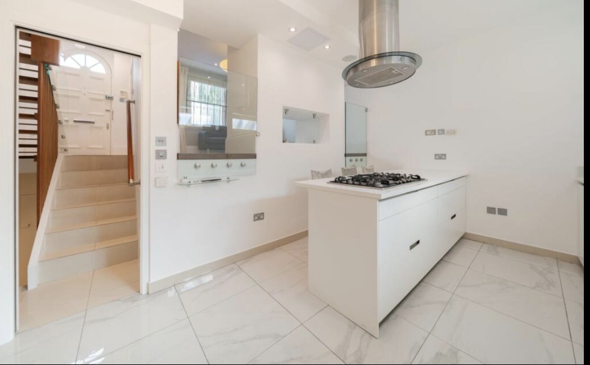 Refurbished open-plan kitchen with white cabinetry, marble floors and a stainless steel range hood
